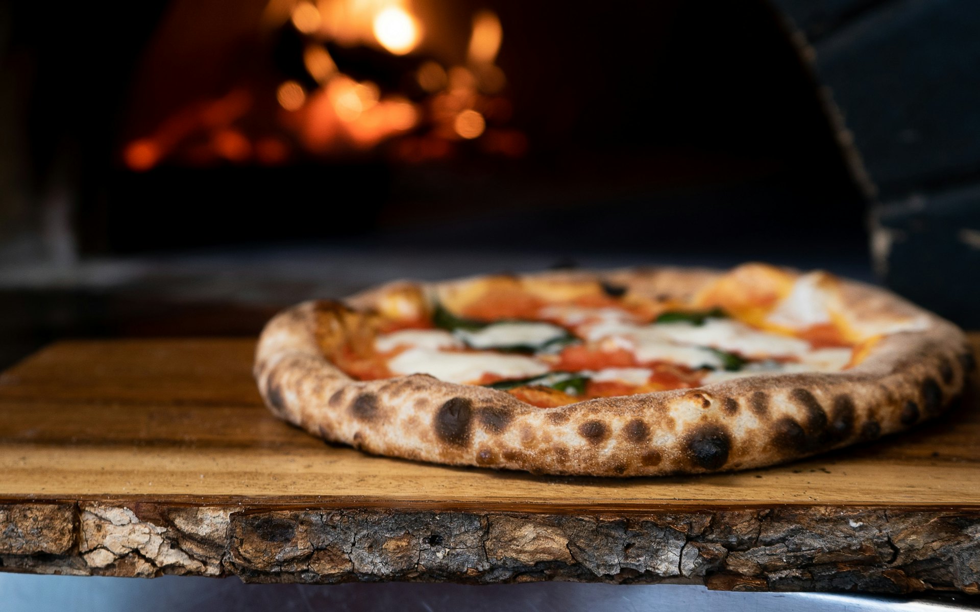 Pizza napoletana appena sfornata davanti alla bocca del forno